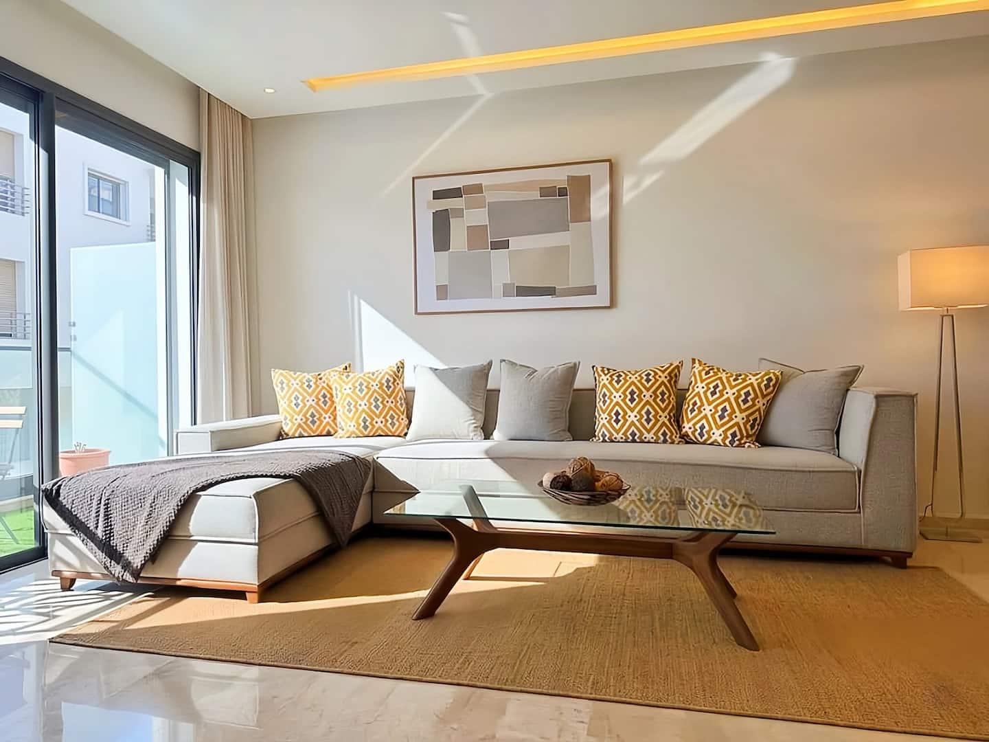 Salon beige élégant avec grande baie vitrée — Maya Suites